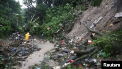 Les résidents nettoient un glissement de terrain sur une route alors que la tempête tropicale Julia frappe le vent et la pluie, à San Salvador, le 10 octobre 2022. REUTERS/Jose Cabezas