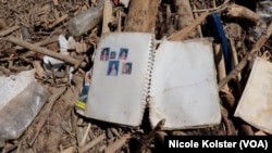 Des photos de famille collées dans un cahier gisent parmi les branches sèches et la boue.