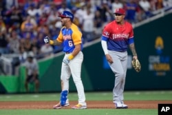 David Peralta (6) du Venezuela célèbre après avoir marqué un doublé contre Eugenio Suarez alors que le joueur de troisième but de la République dominicaine Manny Machado regarde pendant la sixième manche d'un match de la Classique mondiale de baseball, le samedi 11 mars 2023, à Miami.  (AP Photo/Wilfredo Lee)