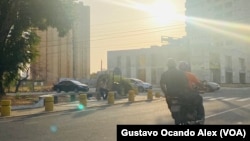 Deux hommes circulent à moto le long de la rue Cecilio Acosta à Maracaibo, tandis que d'autres attendent les transports en commun, dans la matinée de ce lundi 8 mai 2023.