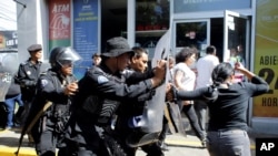 La police anti-émeute expulse des journalistes de l'entrée principale de leur point de vente vers un poste de police à Mangua, au Nicaragua, le 15 décembre 2018.