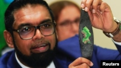 Le président guyanais Irfaan Ali montre à la presse un bracelet à l'effigie d'Essequibo, après avoir rencontré jeudi son homologue vénézuélien Nicolás Maduro à Saint-Vincent-et-les Grenadines.