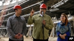 Tareck El Aissami, alors vice-président du gouvernement vénézuélien, écoute le président Nicolás Maduro parler avec son épouse, Cilia Flores, lors d'une visite de la construction du stade de baseball La Rinconada, à Caracas, le 19 mai 2018.