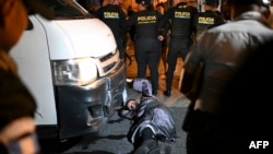 Un membre de la communauté juive Lev Tahor s'accroche à un minibus transportant certains des enfants sauvés pour l'empêcher de poursuivre sa marche vers l'école spécialisée Alida España de Arana à Guatemala City, le 22 décembre 2024.