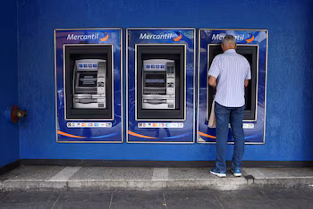 Un homme prend de l'argent à un guichet automatique, à Caracas, Venezuela le 10 février 2023. REUTERS/Gaby Oraa