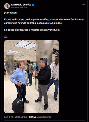 Juan Pablo Guanipa, en chemise bleue, tient une valise. Un journaliste l'interviewe au micro dans un aéroport, avec d'autres personnes en arrière-plan