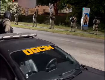 voiture noire avec "DGCIM" sur le pare-brise et la barre lumineuse sur le toit, garés la nuit devant des soldats en tenue de camouflage à côté d'une rue