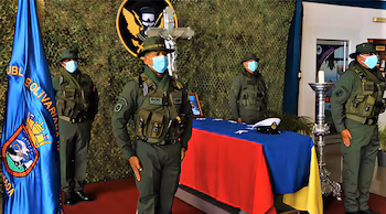 Quatre soldats en uniforme, masqués, rendent hommage devant un cercueil recouvert du drapeau vénézuélien et d'une casquette navale