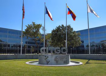 Immeuble Citgo avec son enseigne et sa fontaine. Quatre drapeaux flotteront : les États-Unis, le Texas, le Venezuela et un drapeau blanc avec le logo de l'entreprise.