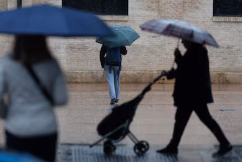 Plusieurs personnes se protègent de la pluie, ce samedi à Valence. (EFE/Kai Forsterling)