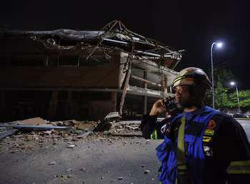 Un pompier se tient à côté d'un bâtiment endommagé qui abritait, il y a plusieurs années, une université, après un fort tremblement de terre, à Valence (Venezuela), le 24 juin 2026 (REUTERS/Juan Carlos Hernández)