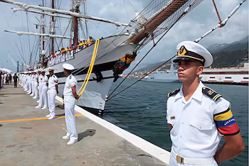 Officier de la marine vénézuélienne en uniforme blanc au premier plan. Rangée d'officiers, voilier avec des gens, jetée, eau, montagnes et un autre navire en arrière-plan