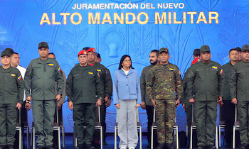 Delcy Rodríguez debout parmi des soldats en uniforme, certains avec des casquettes et des bérets, devant une pancarte indiquant "Prestation de serment du nouveau haut commandement militaire"