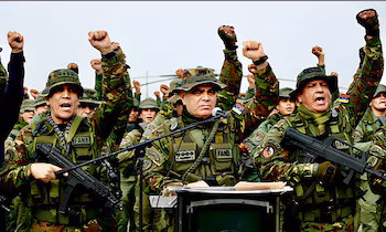 Plusieurs soldats en uniforme de camouflage tiennent des armes et lèvent les poings fermés devant un pupitre équipé de microphones