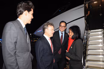 Delcy Rodríguez parle à un groupe d'hommes en costume à côté des marches d'un avion la nuit