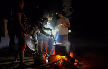 Des habitants préparent de la soupe sur un feu de bois extérieur lors d'une panne d'électricité suite à un problème dans une grande centrale électrique, à La Havane, Cuba, le 19 octobre 2024. (AP Photo/Ramón Espinosa)