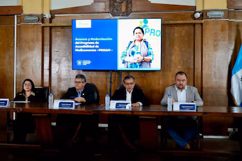 Un homme s'exprime sur un podium devant un écran montrant des cartes du Guatemala avec les chiffres des ouvertures de pharmacies de 2024 à 2026.