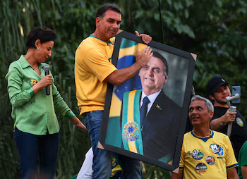 Le candidat présidentiel brésilien Flavio Bolsonaro du Parti libéral (PL) tient un portrait de son père, l'ancien président brésilien Jair Bolsonaro, lors d'un rassemblement électoral à Goiânia, au Brésil. REUTERS/Adriano Machado